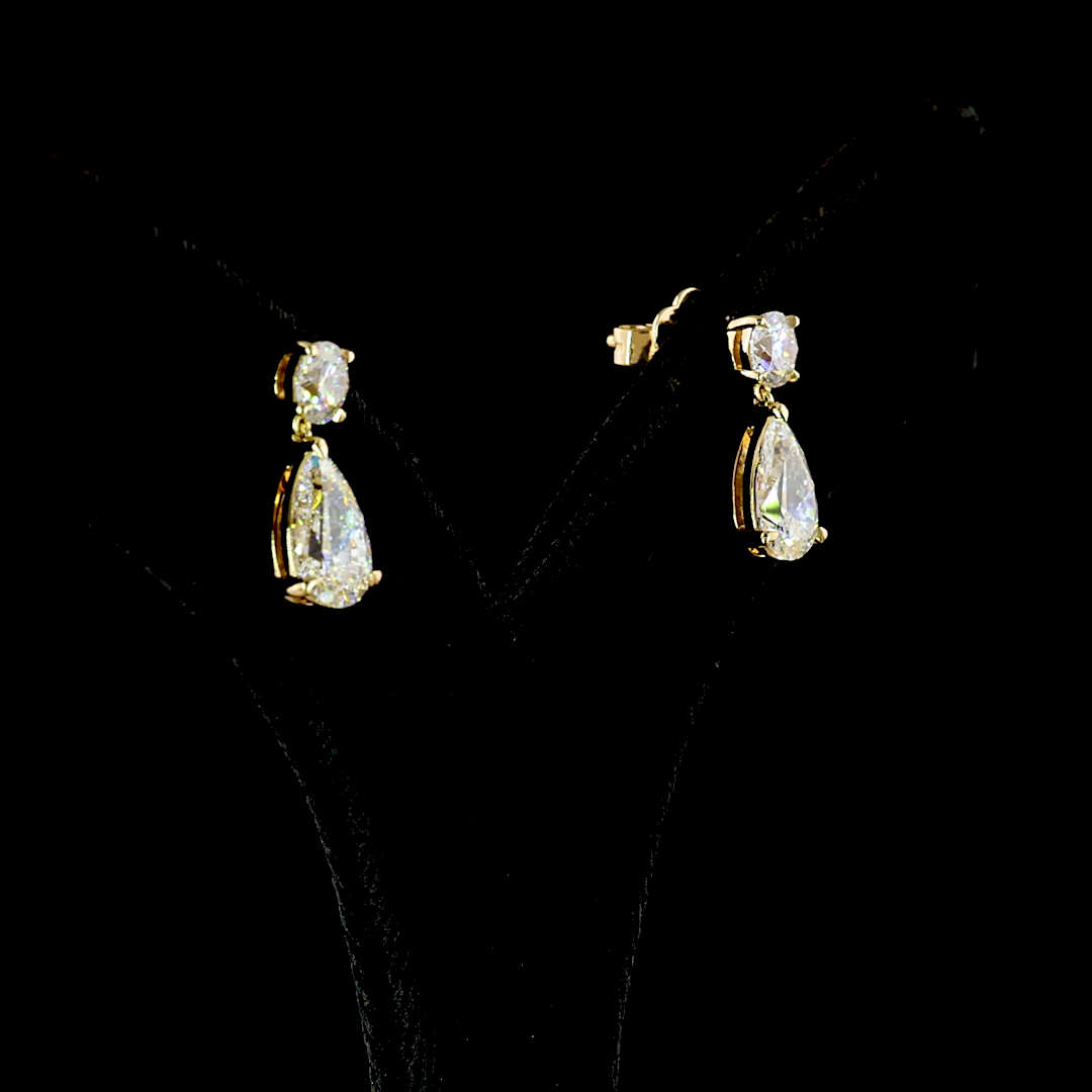 2.90ctw lab grown pear and round diamond drop earrings in 14k yellow gold on a black display.
