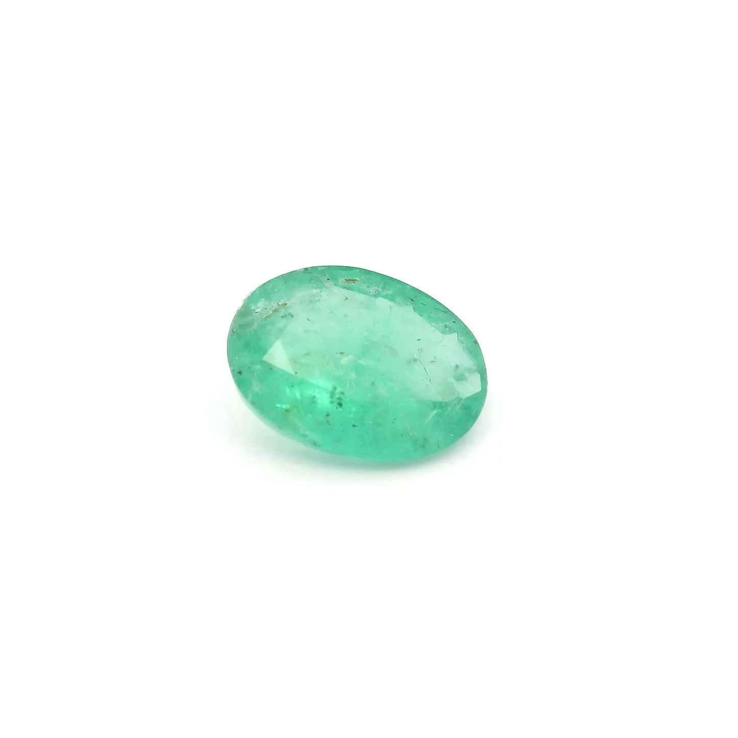 Oval faceted natural emerald gemstone with green color and moderate inclusions.