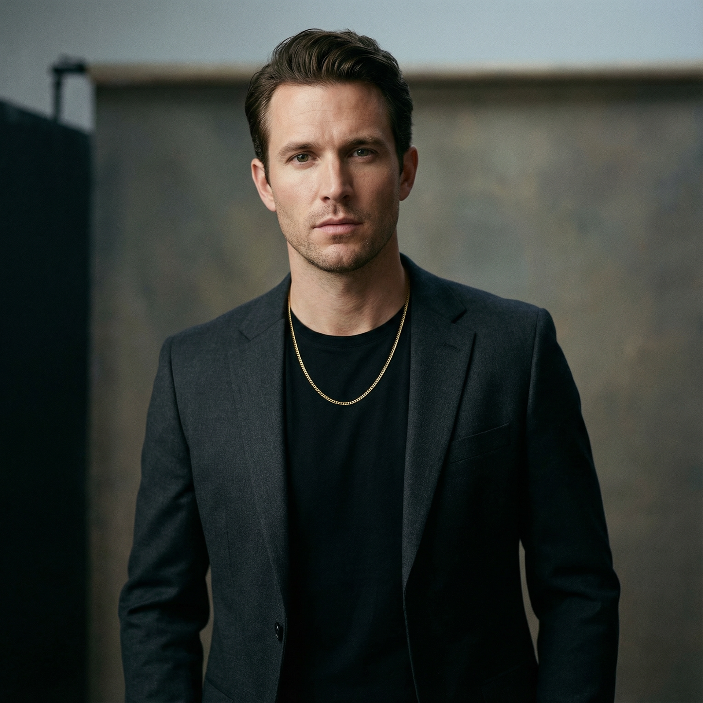 A man wearing a 3.5mm domed curb link chain in yellow gold over a black t-shirt and blazer.