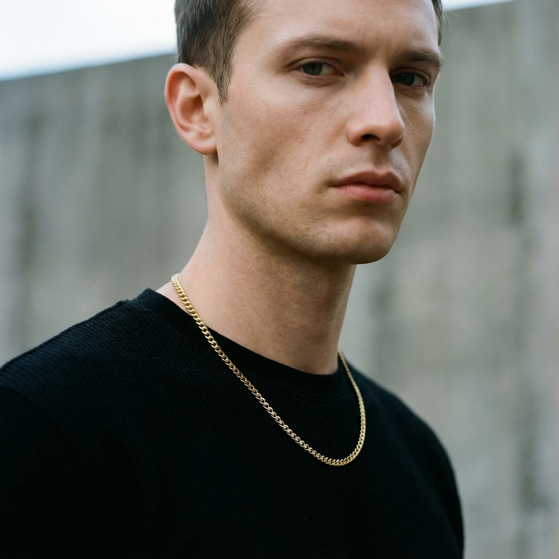 A man wears a 4.2mm domed curb link chain in polished yellow gold over a black sweater.