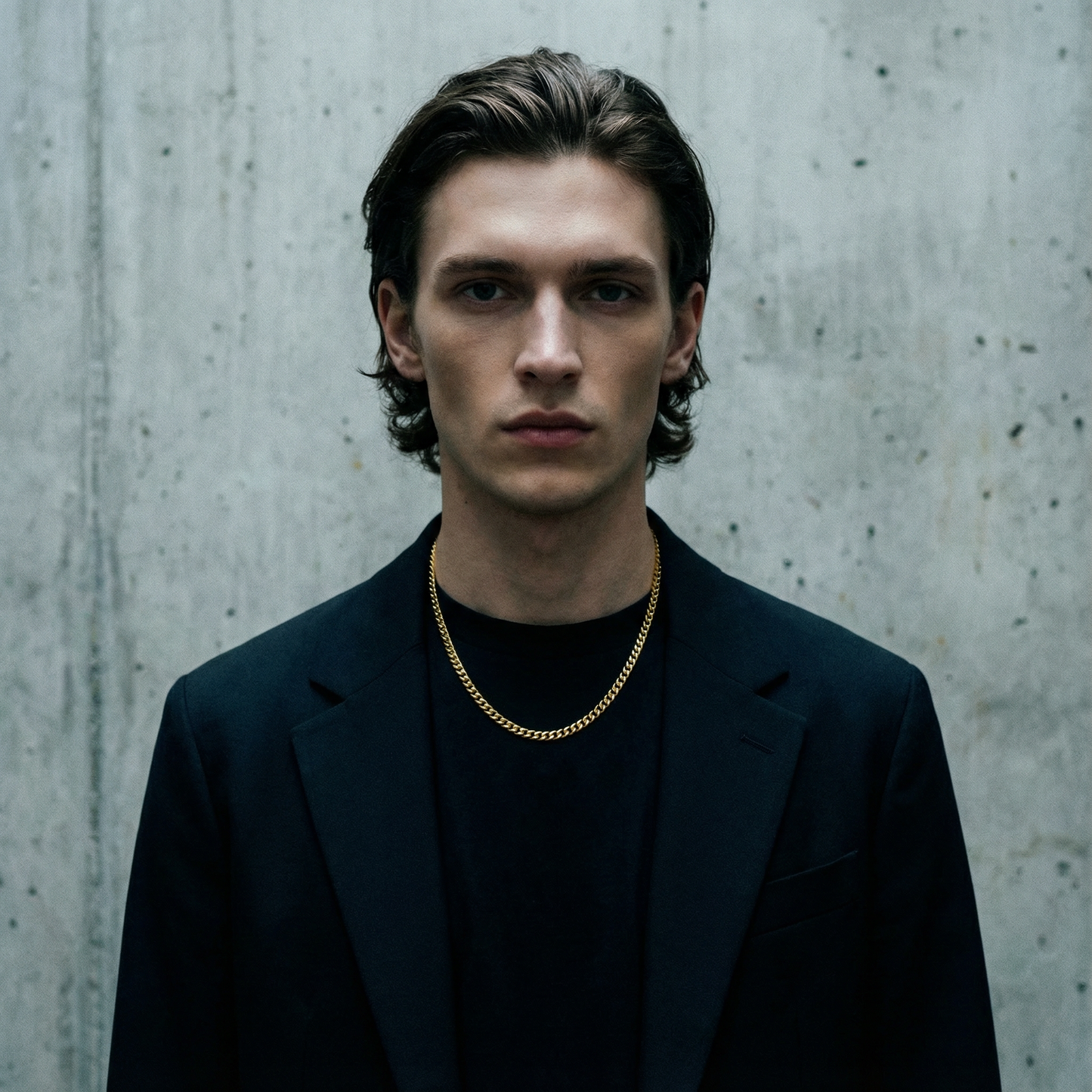 A man wearing a 5.6mm domed curb link chain in yellow gold over a black blazer.