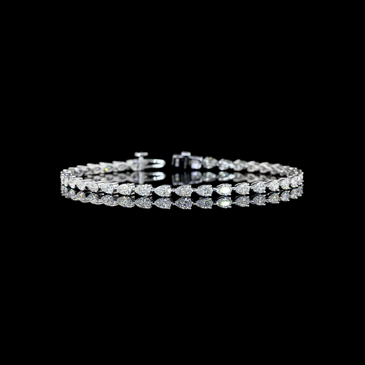 3.98ctw lab grown pear cut diamond tennis bracelet in 14k white gold on a black background.