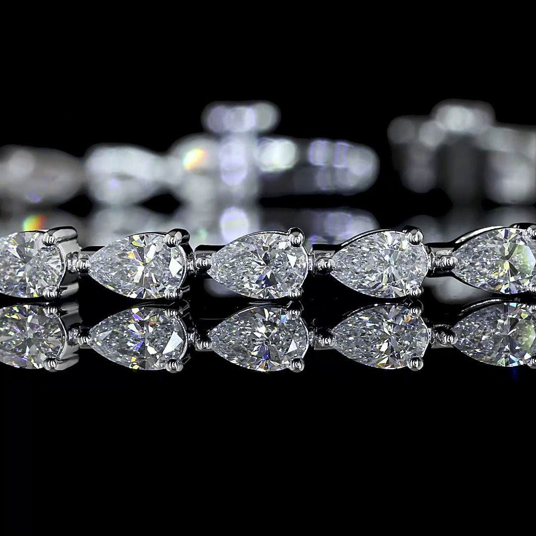 Lab grown pear cut diamond tennis bracelet in 14k white gold on a reflective black surface.