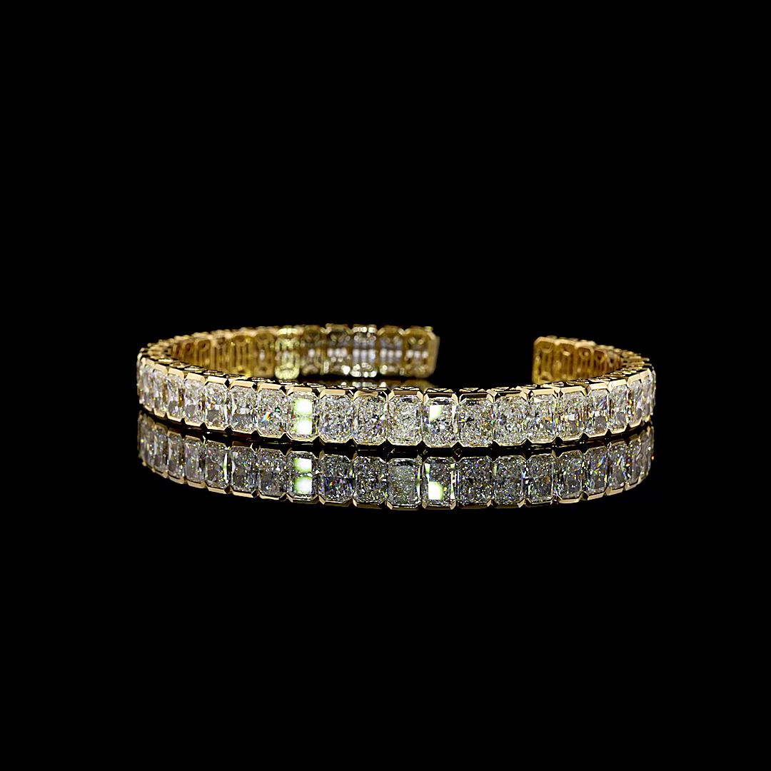 26.37ctw lab grown radiant cut diamond cuff bracelet in 14k yellow gold on a black background.