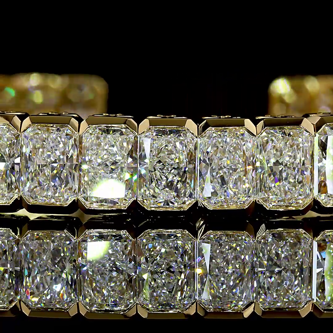 Close-up of a 14k yellow gold cuff bracelet featuring radiant cut lab grown diamonds.
