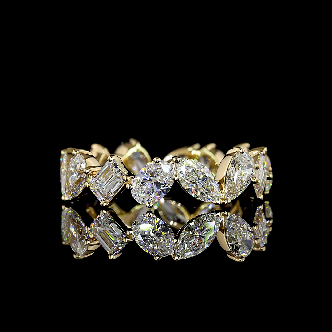 Lab grown mixed shape diamond eternity ring in 14k yellow gold on a reflective black surface.