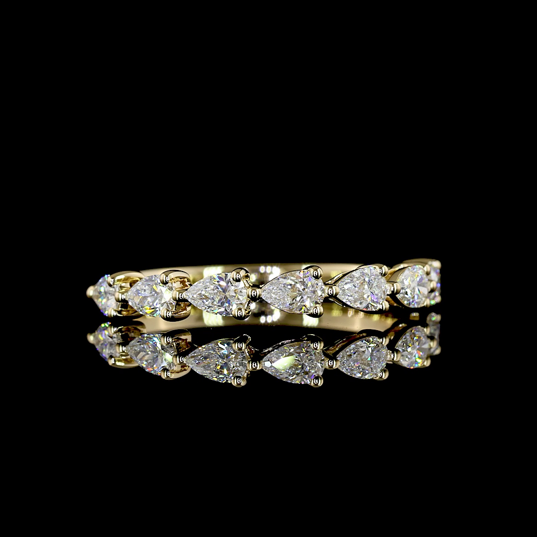 0.63ctw lab grown pear diamond half eternity band in 14k yellow gold on a black background.