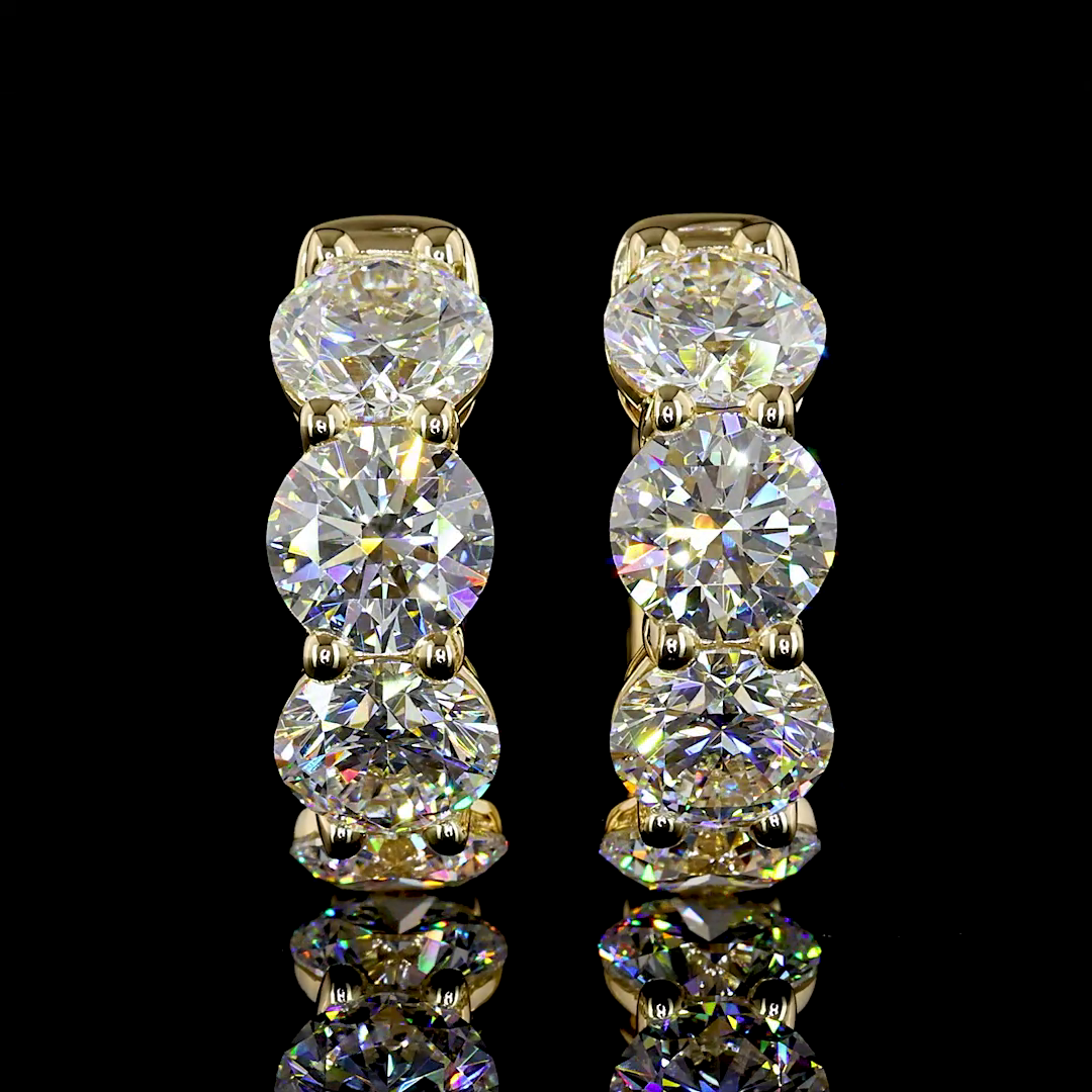 A pair of 14k yellow gold huggie earrings featuring three large round lab-grown diamonds each.