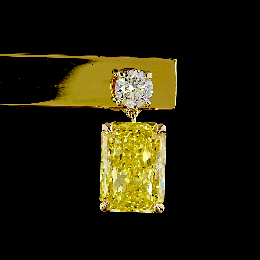 14k yellow gold earring with a round white diamond above a large radiant-cut yellow diamond.