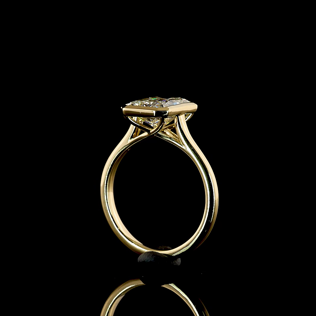 Side view of a 3.17ct radiant cut lab diamond engagement ring in a 14k yellow gold bezel setting.