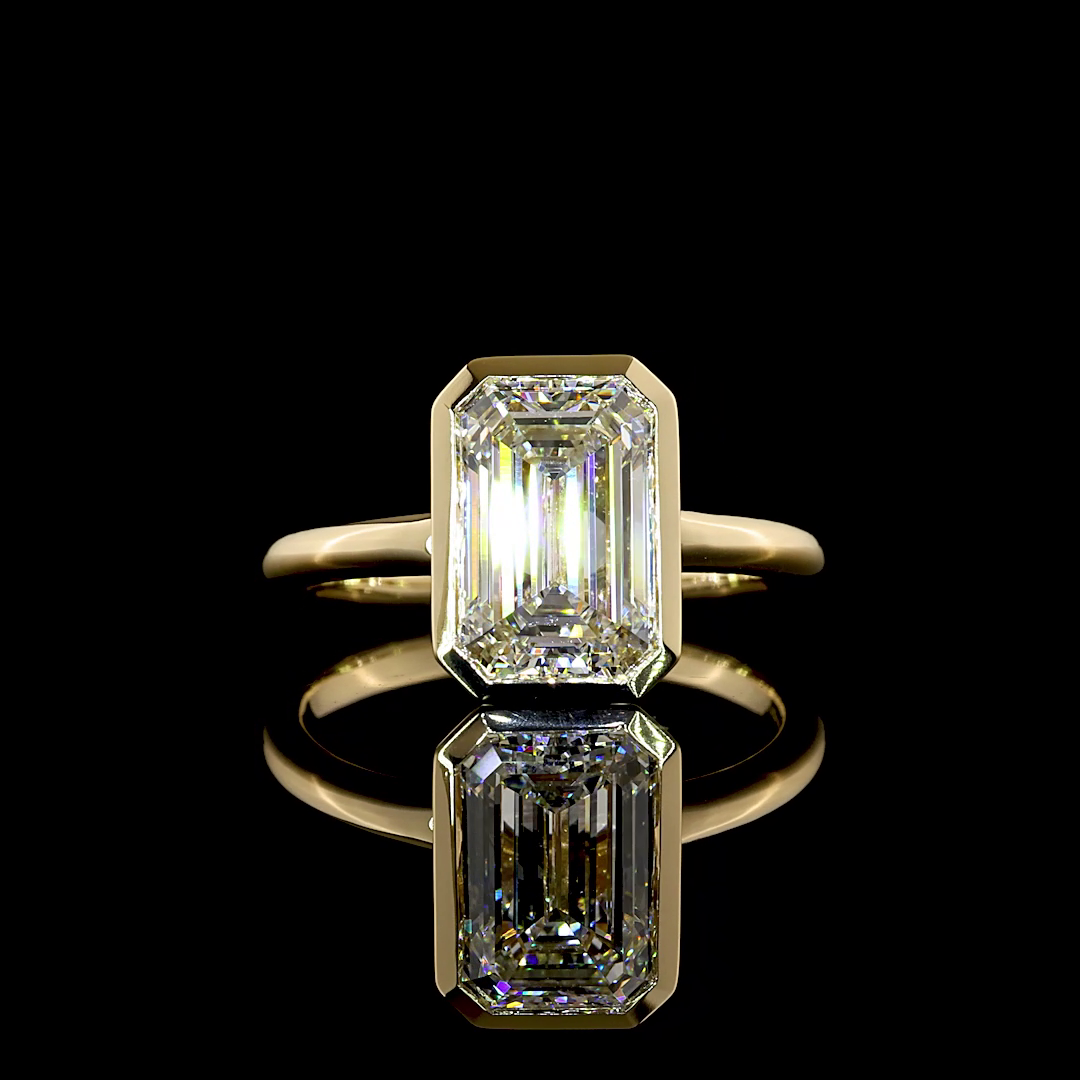 2.77ct emerald cut lab grown diamond engagement ring in a 14k yellow gold bezel setting.