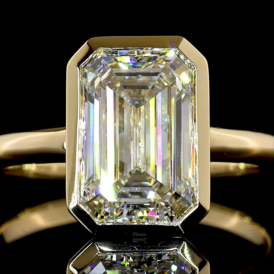 2.77ct lab grown emerald cut diamond engagement ring in a 14k yellow gold bezel setting.