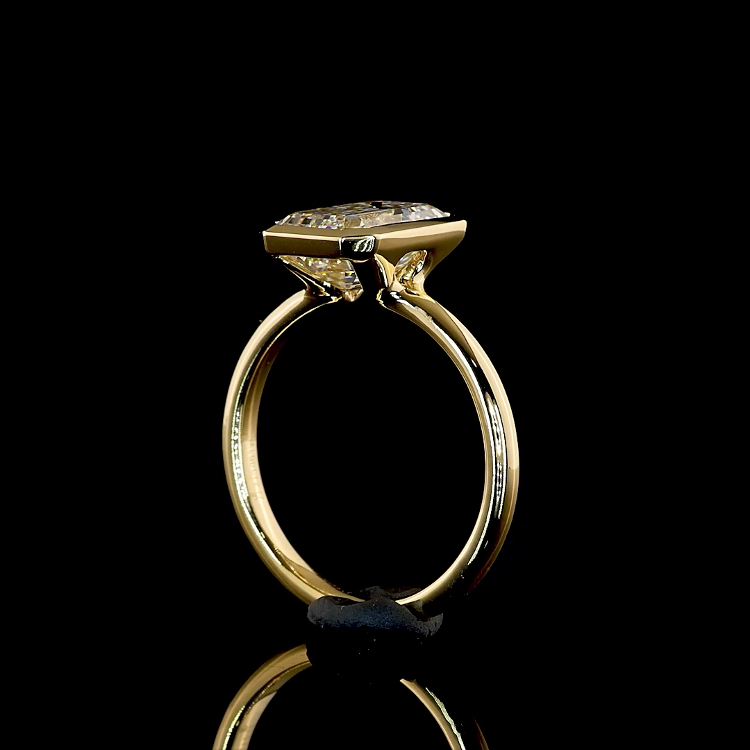 Side view of a 2.77ct emerald cut lab grown diamond engagement ring in a 14k yellow gold bezel setting
