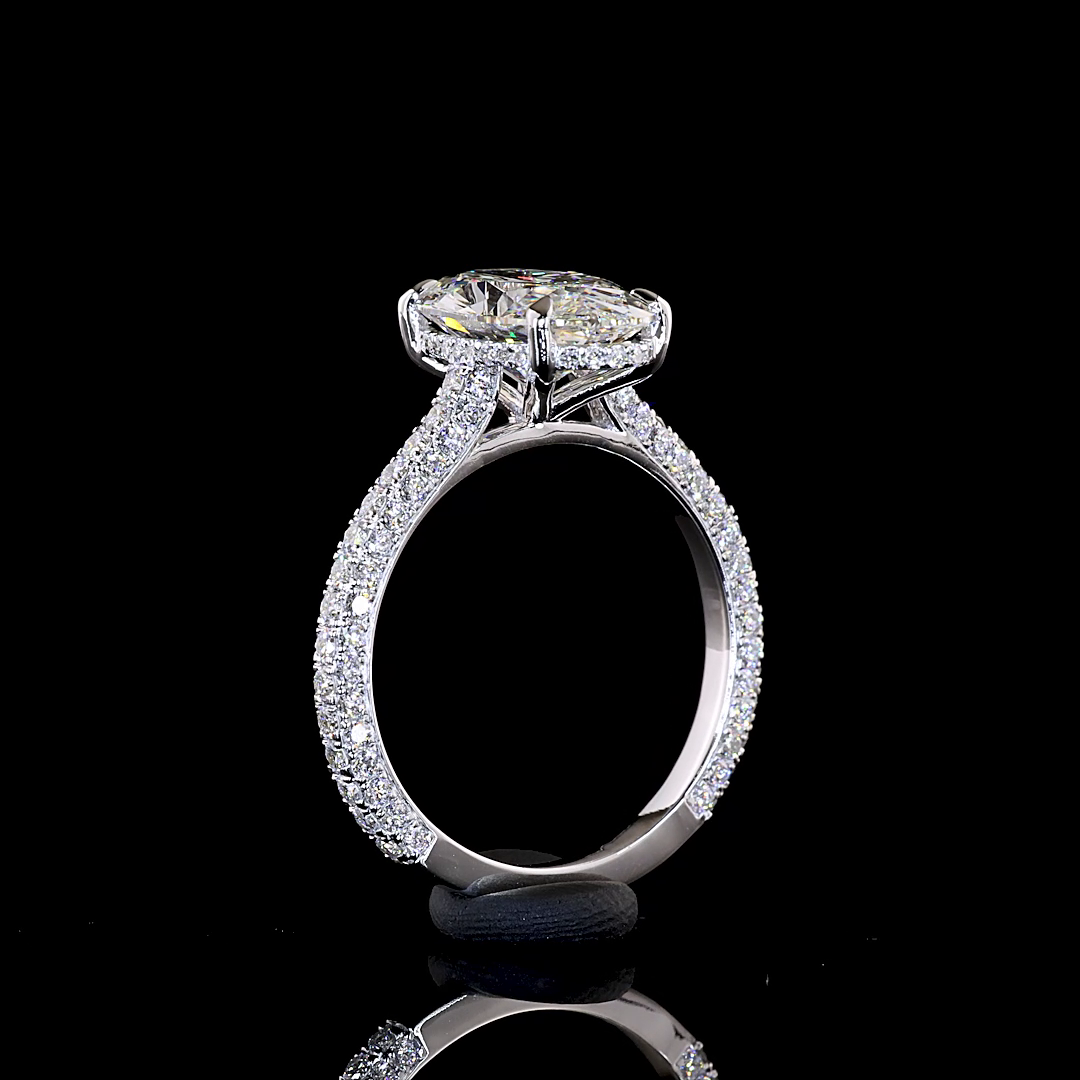 Side view of a 14k white gold engagement ring with a moval cut diamond and three-sided pavé band.