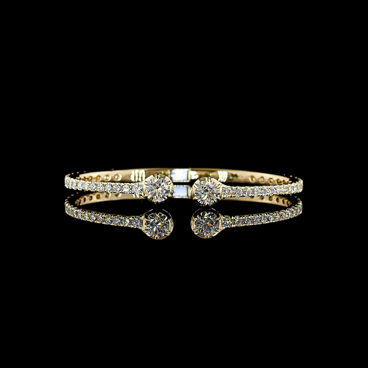 A 14k yellow gold and lab grown diamond hinged cuff, rotating in a 360 video on a black background. There are two large round diamonds at the front with an open area between them, then a thin diamond-set bar circling around the cuff.