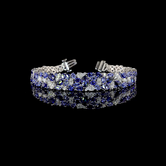 A white gold bracelet rotating on a black background. It is set with an array of lab grown sapphires and lab grown diamonds in various shapes and sizes, tapering down towards the bottom of the wrist. It has a secure tongue closure with a locking bar.