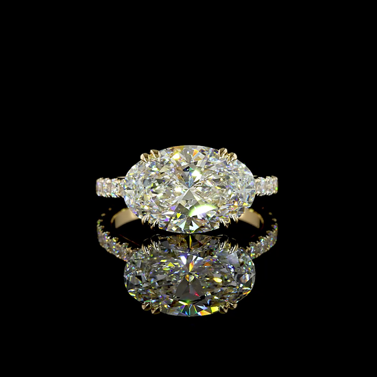 A yellow gold lab grown diamond engagement ring rotating on a black background. It is set with a 4.26ct oval cut lab grown diamond with double cat claws in an east-west (horizontal) orientation. The band is a cathedral design with lab grown diamonds extending halfway around the ring.
