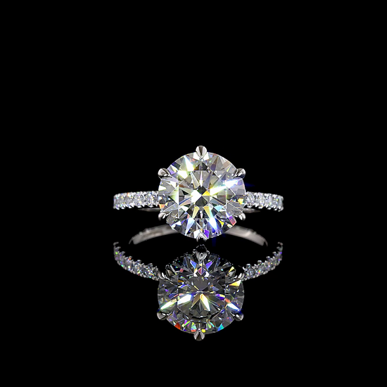 A platinum engagement ring, rotating 360 degrees on a black background. It is 6 prong set with a 3.01ct round cut lab grown diamond, which is surrounded on the sides of the setting with a hidden halo. The band is thin and set with lab grown diamonds halfway around.